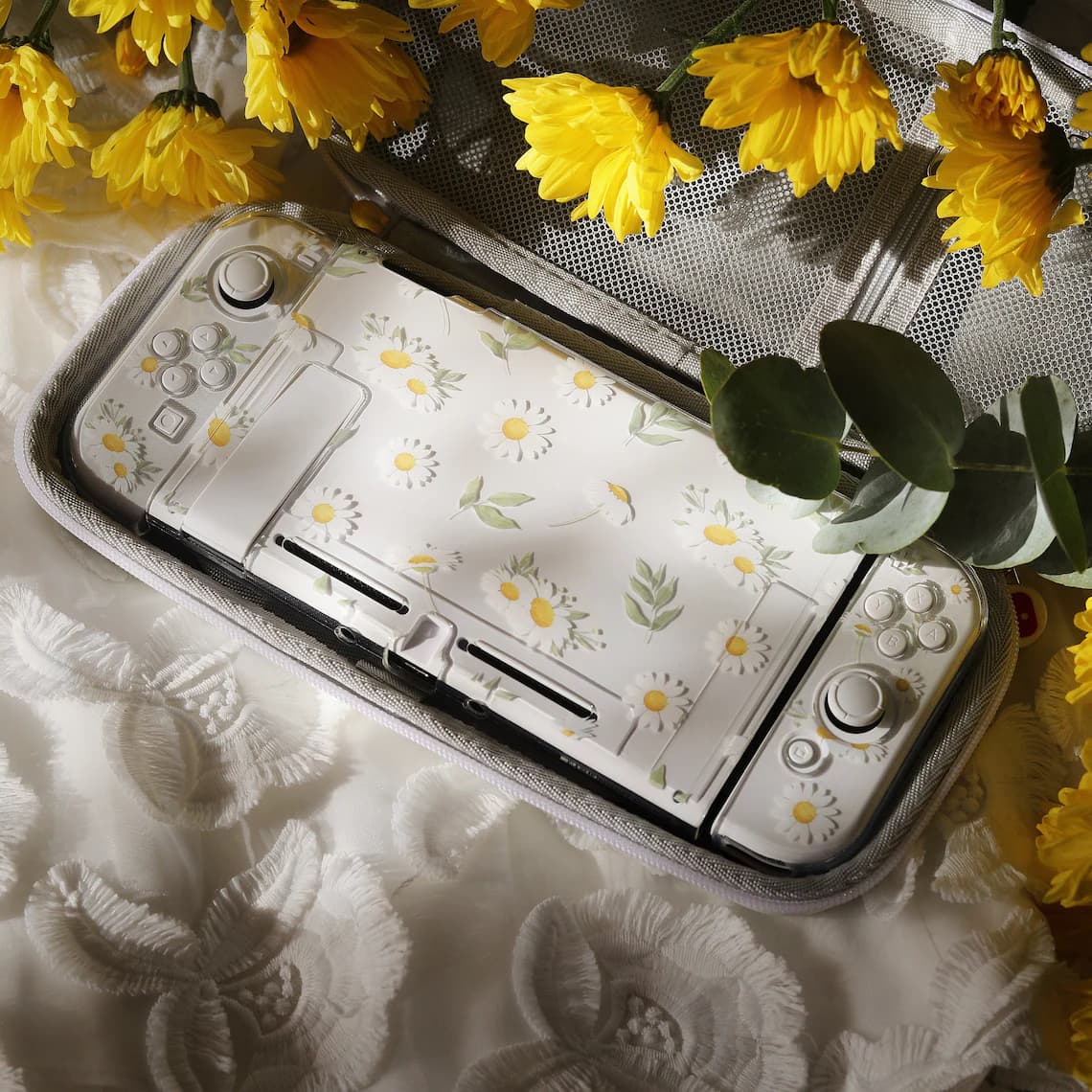 Nintendo Switch with clear Daisy Daydream case sitting inside a fabric carrying pouch, styled with yellow flowers