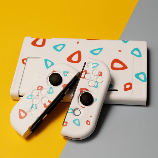 White Nintendo Switch Egg soft-shell case and Joy-Con covers with red and teal eggshell pattern, styled on yellow and grey background