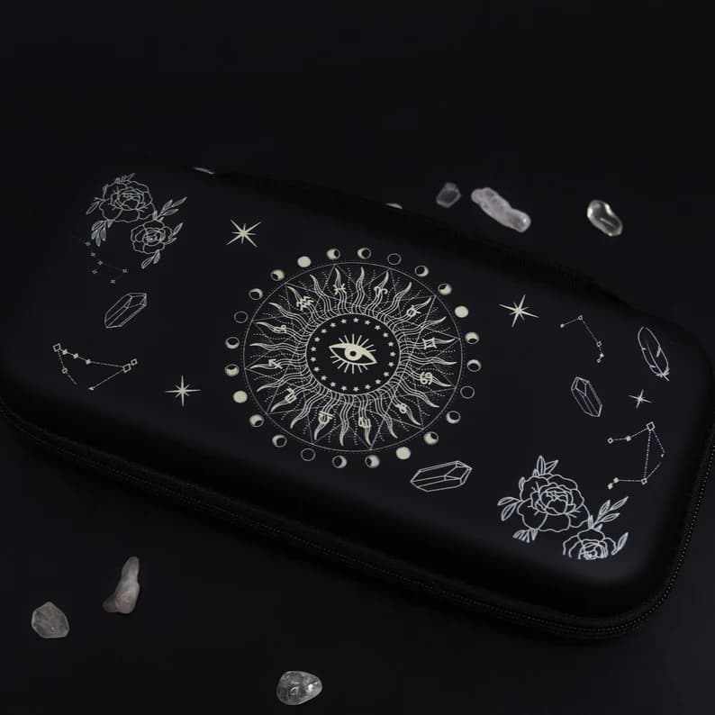 Black Nintendo Switch Solaris Noire carrying case with white celestial sun eye, constellation and rose design, styled with crystals