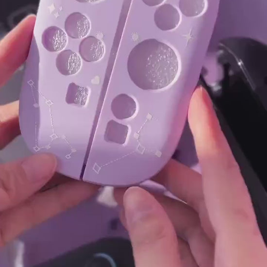 Short video of hands holding a Cosmic Moon Joy-Con back plate with constellation print on lilac, with a Switch and Joy-Cons in the background.