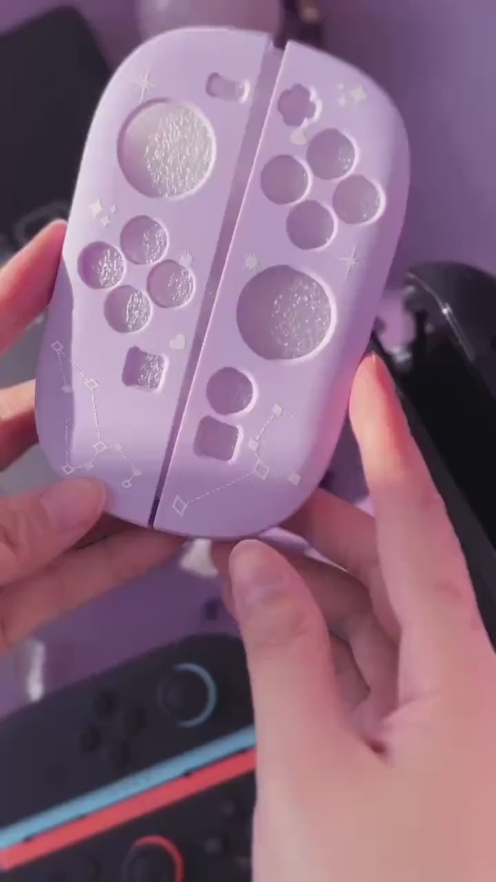 Short video of hands holding a Cosmic Moon Joy-Con back plate with constellation print on lilac, with a Switch and Joy-Cons in the background.
